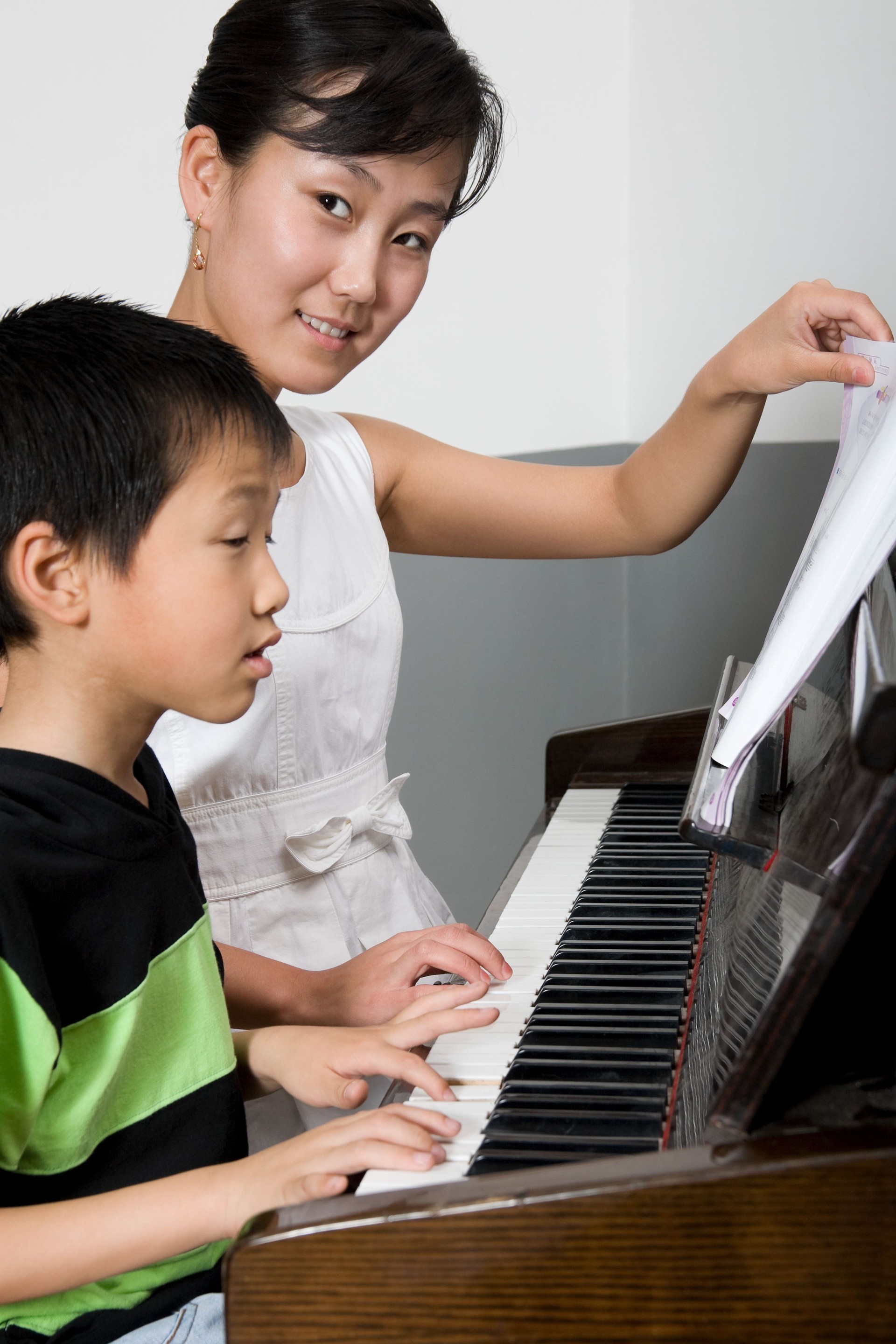 A teacher helping a student play the piano