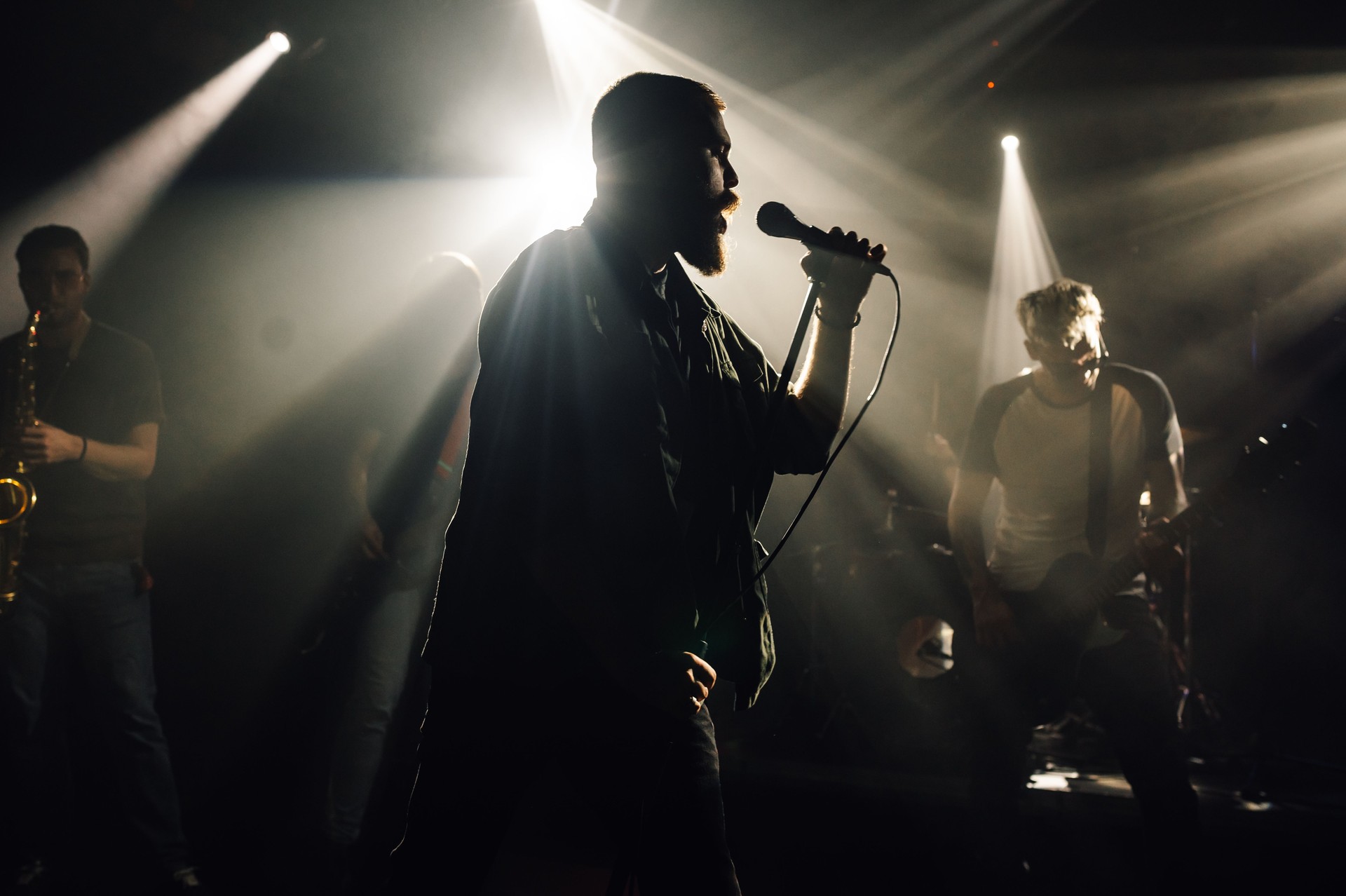 Singer performing with band on stage under stage lights